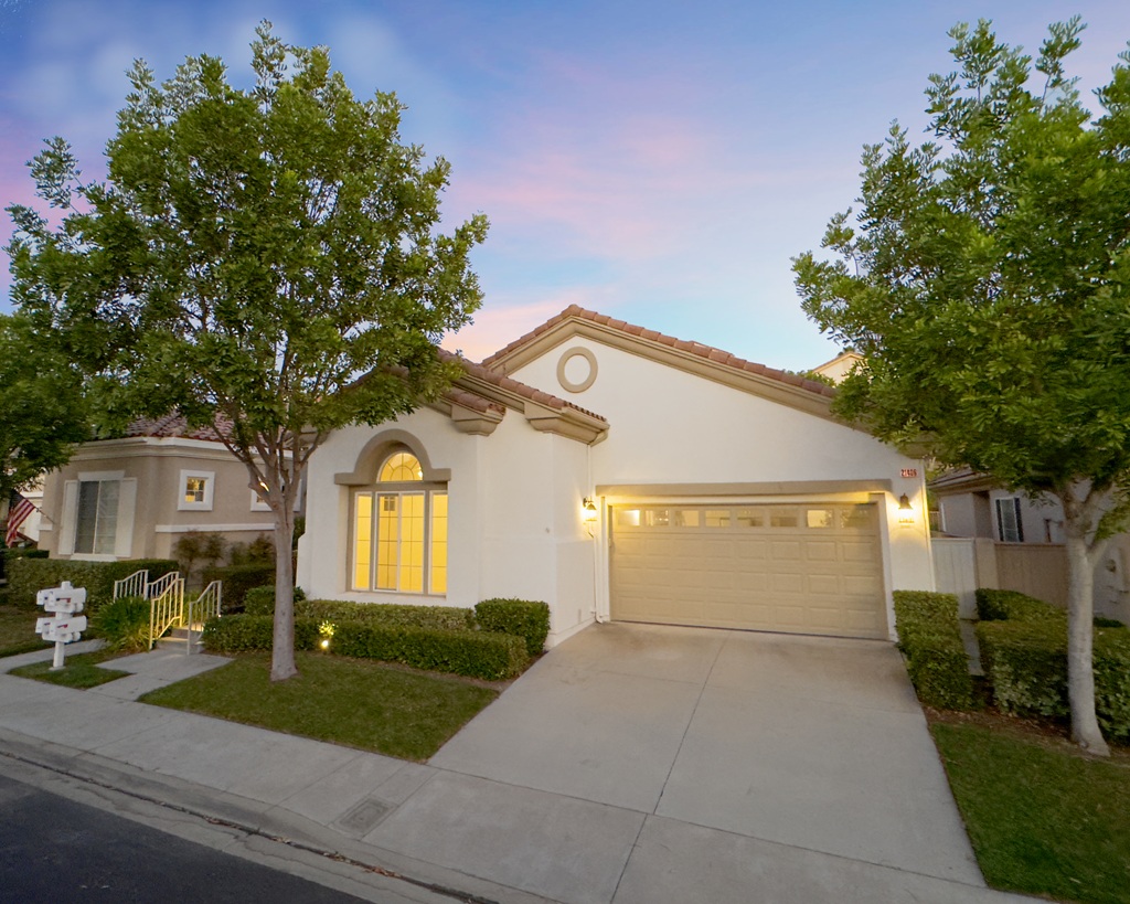 Front of a single story home in the evening with the lights on inside.