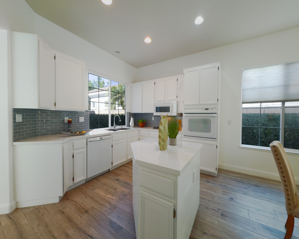 A kitchen with white cabinets and a wood floor