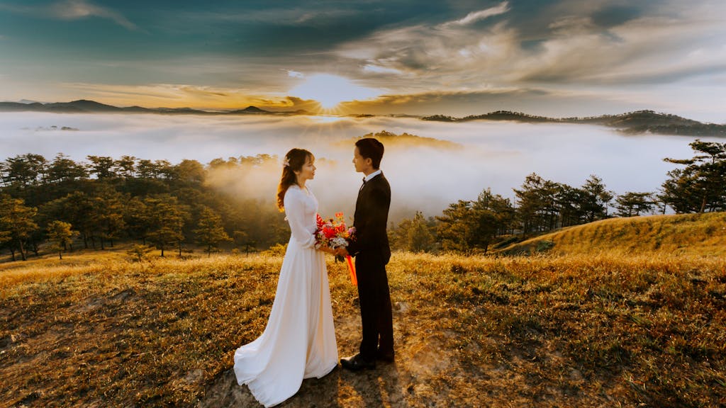 A bride and groom embrace amidst a sea of clouds at sunset in Đà Lạt, creating a romantic scene.