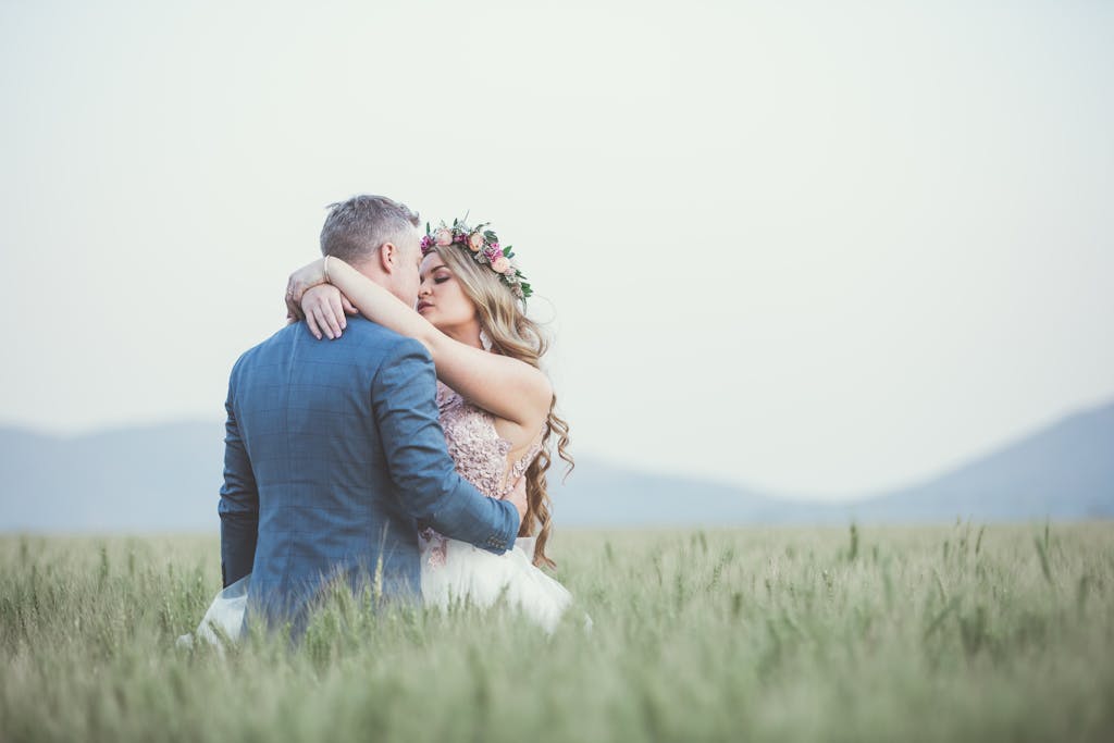 A couple embracing romantically in a lush summer field, showcasing love's beauty.