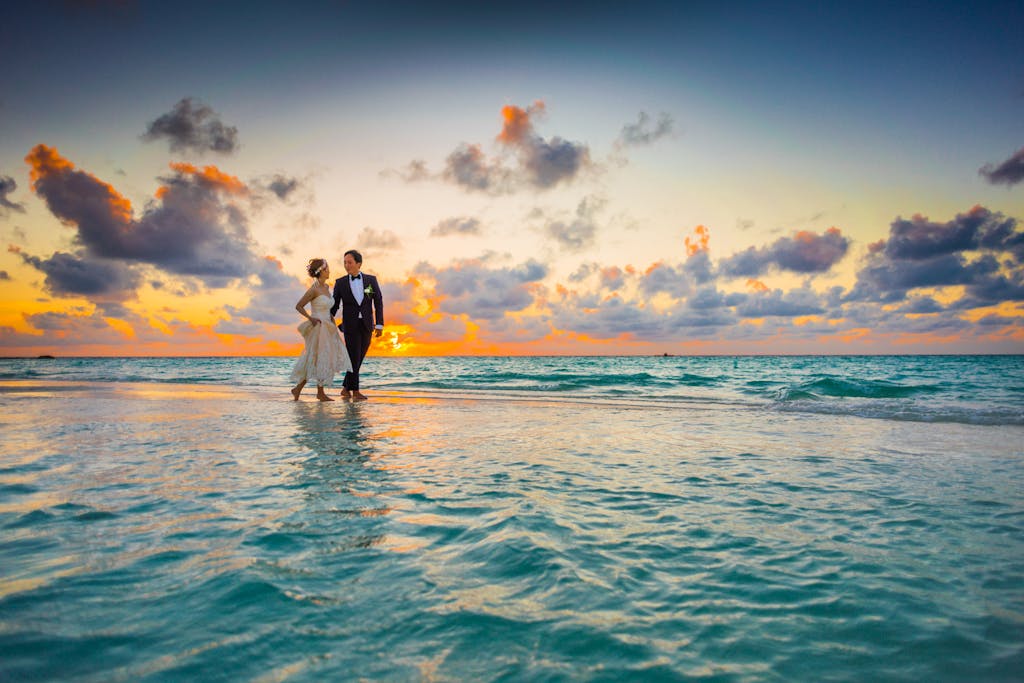 A young couple enjoying a romantic beach wedding during a vibrant sunset.