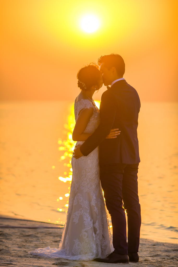 Captivating moment of a couple sharing a kiss during a beach sunset wedding, exuding romance.