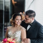 joyful wedding portrait of a young couple indoors holding a vibrant bouquet. 1560303